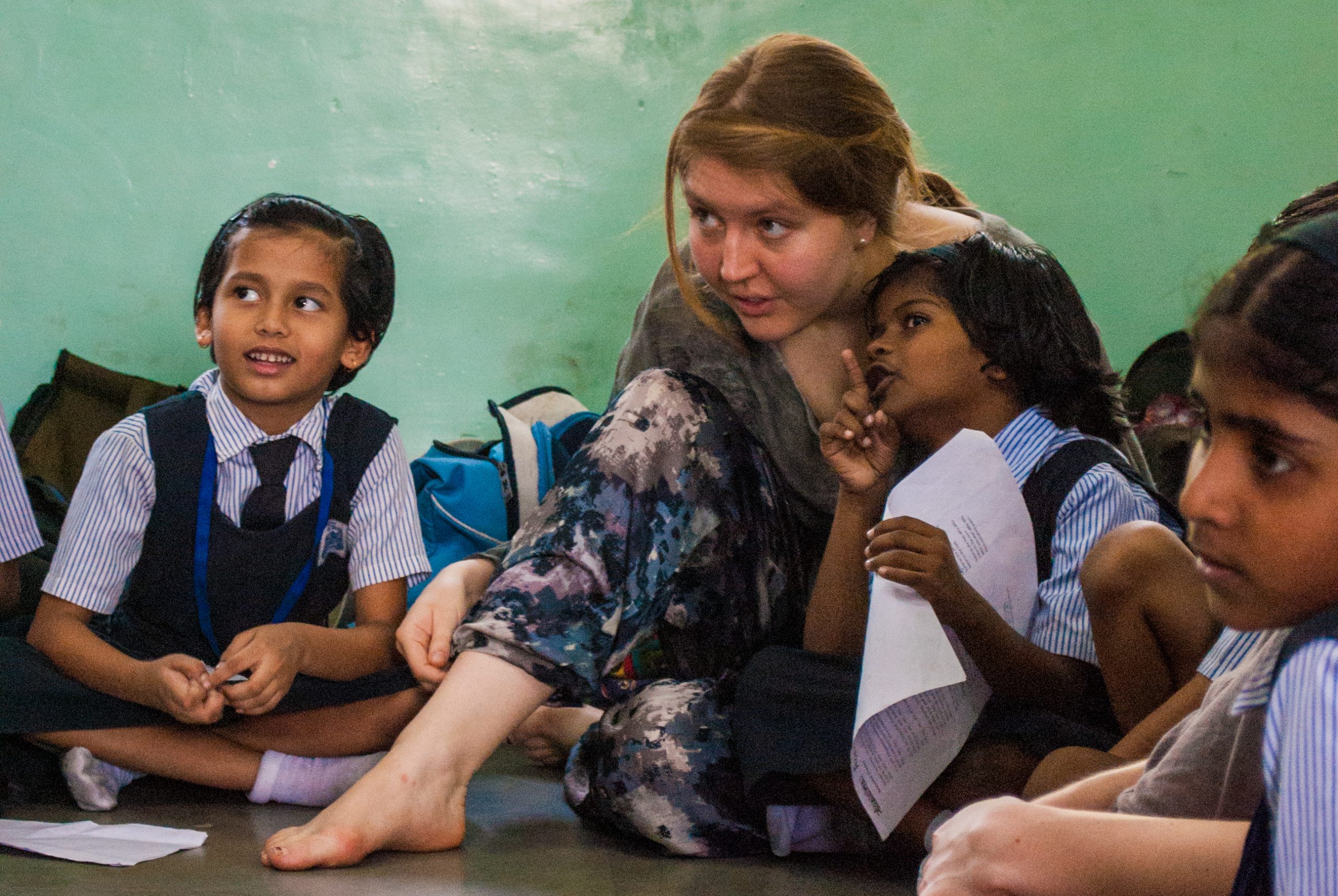 Tour member sitting and working with local students from India