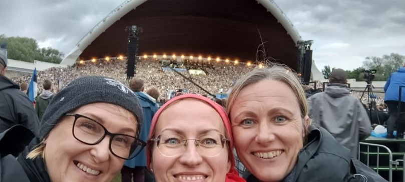 Three couriers standing in front of a large crowd at Laulupidu