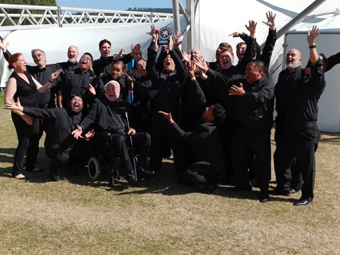A choir in all black celebrating with hands in the air